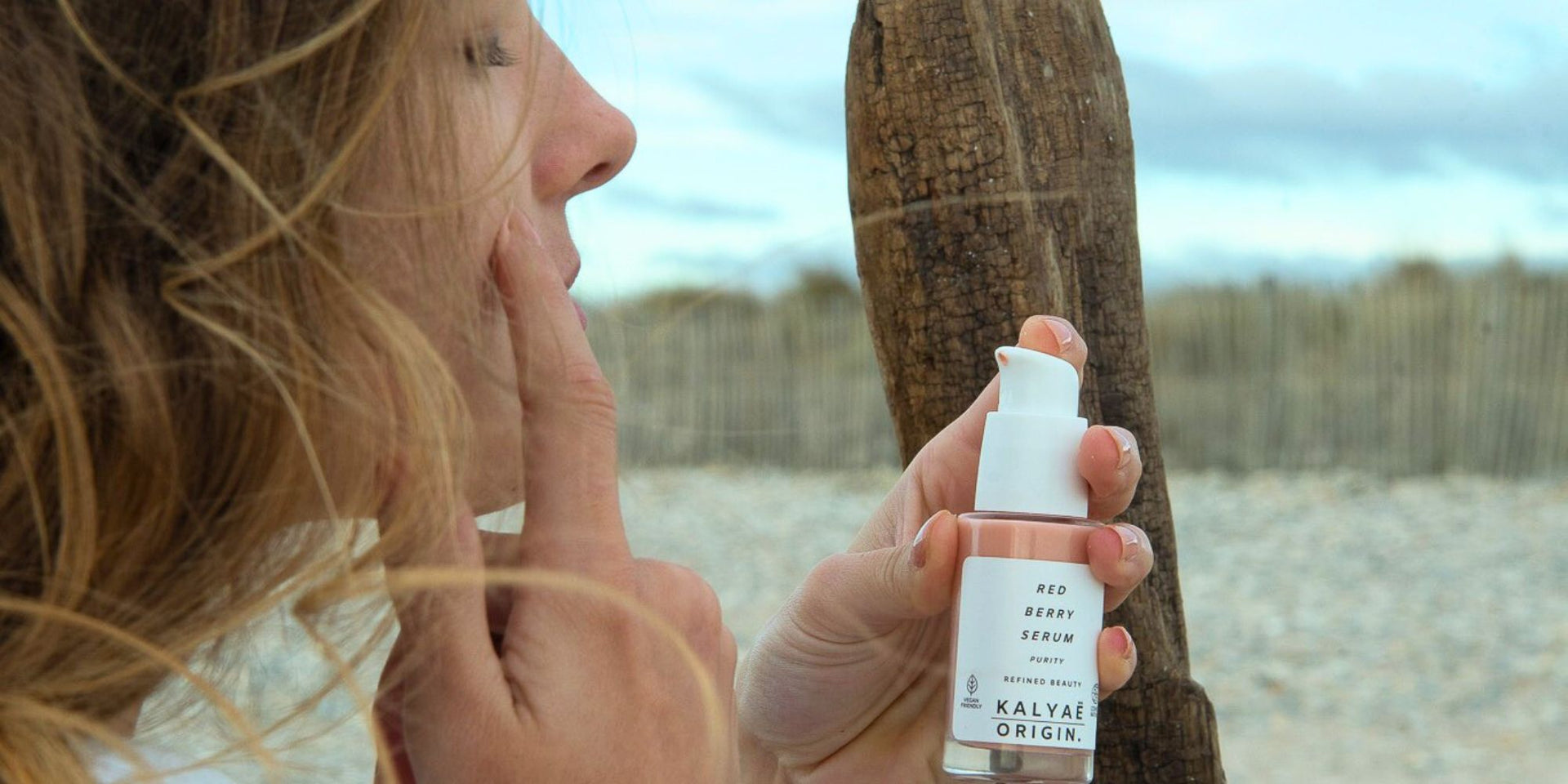 Red Berry Serum sérum apaisant pour peaux sensibles certifié COSMOS NATURAL 30 ml présenté en application en extérieur sur la plage – KALYAË ORIGIN