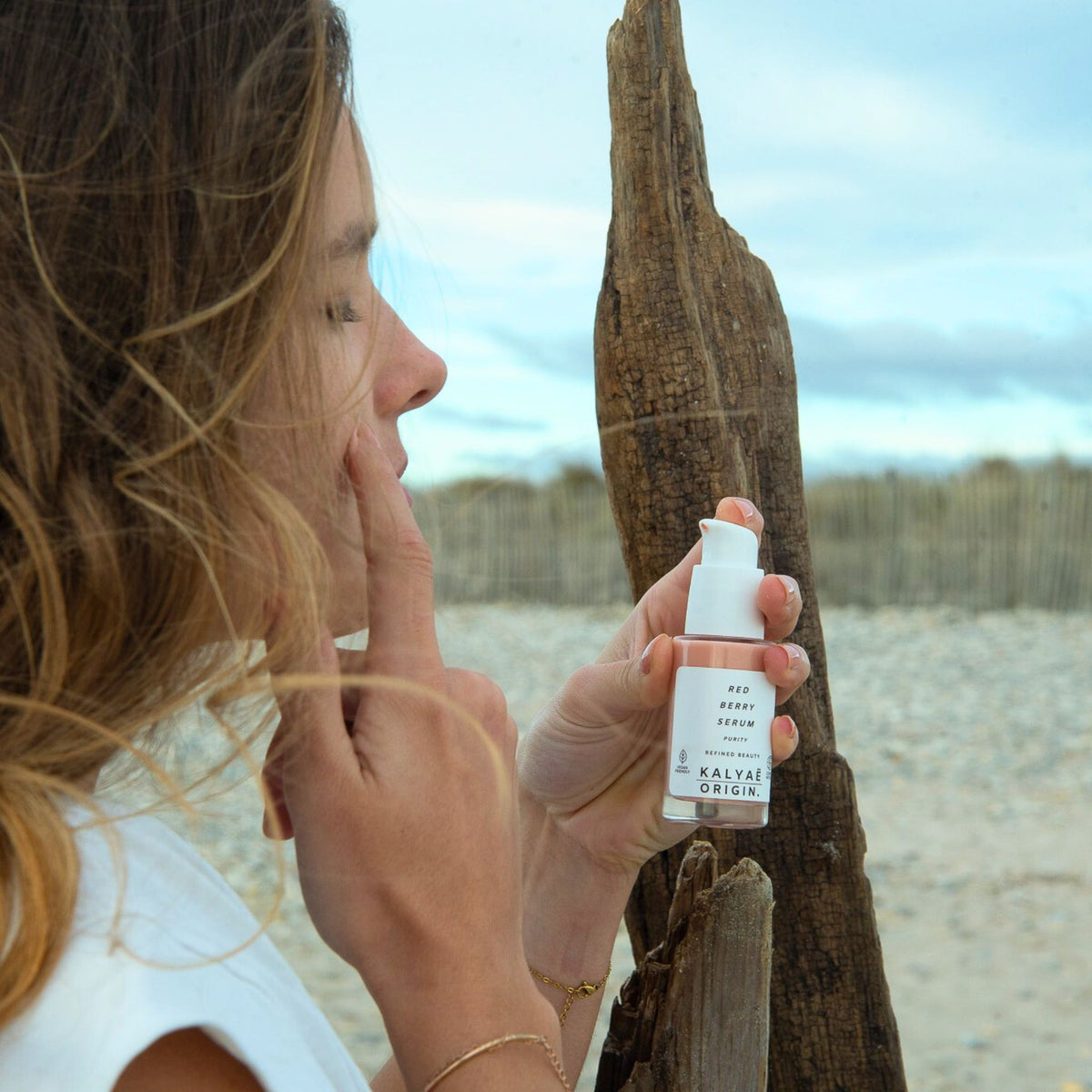 Red Berry Serum sérum repulpant certifié COSMOS NATURAL 30 ml présenté en application en extérieur sur une plage – KALYAË ORIGIN